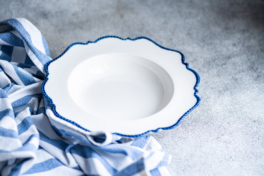 Empty white plate with blue edge on a textured background