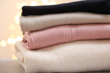 Stack of folded clothes on grey table against blurred lights, closeup