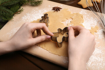 Woman making Christmas cookies with cutters at wooden table, closeup