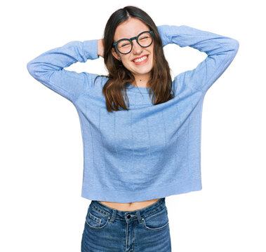 Young beautiful woman wearing casual clothes and glasses relaxing and stretching, arms and hands behind head and neck smiling happy