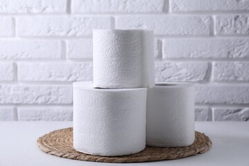 Toilet paper rolls on white table against brick wall
