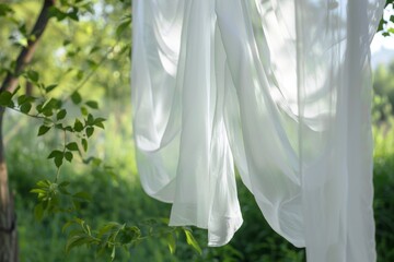 White sheets hanging in a backyard with a green nature backdrop seen up close