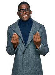 Young african american man wearing business clothes and glasses doing money gesture with hands,...