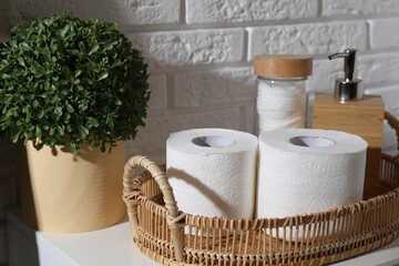 Toilet paper rolls, floral decor, dispenser and cotton pads on table indoors