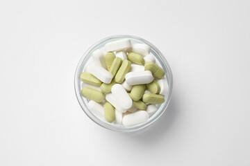 Different vitamin pills in bowl on white background, top view