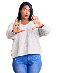 Hispanic woman with long hair wearing casual clothes moving away hands palms showing refusal and...