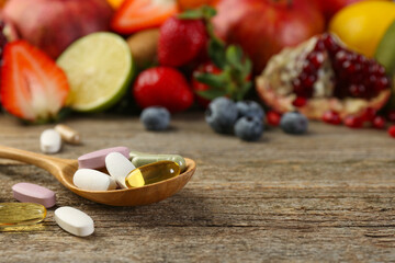 Different vitamin pills and fresh fruits on wooden table. Space for text
