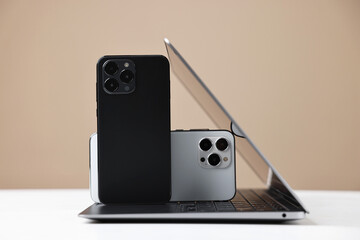 Modern laptop and smartphones on beige background