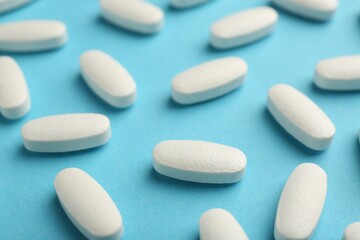 Obraz na płótnie Canvas Vitamin pills on light blue background, closeup