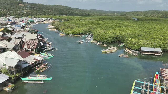 Aerial video of boats anchored in the sea near wooden houses in a fishing village, Socorro