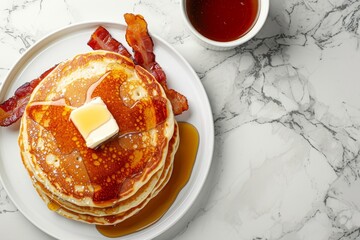 Flat lay banner design of scrumptious pancakes topped with maple syrup butter and crispy bacon on a white marble table