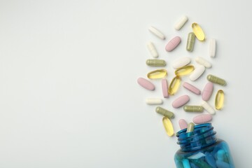 Vitamin pills and bottle on light background, top view. Space for text