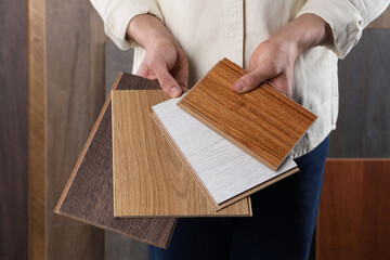 Man with different samples of wooden flooring indoors, closeup