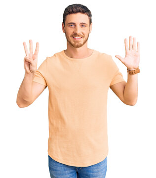 Handsome young man with bear wearing casual yellow tshirt showing and pointing up with fingers number eight while smiling confident and happy.