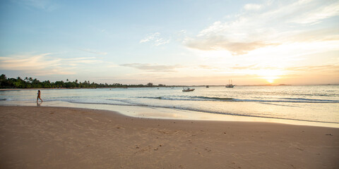 Praia do nordeste brasileiro com banhistas e luz suave de entardecer