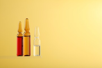 Glass ampoules with liquid on yellow background. Space for text