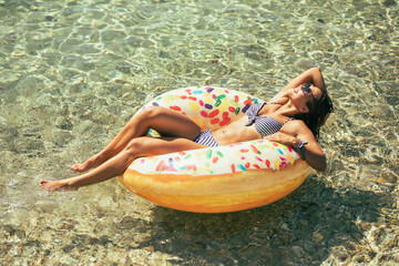 Woman Laying on Inflatable Donut in Water