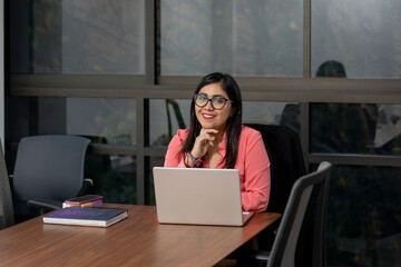 Smiling business woman sitting in her office. Mexican businesswoman at her desk