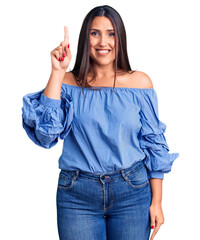 Young beautiful brunette woman wearing casual t-shirt pointing finger up with successful idea. exited and happy. number one.