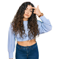 Young hispanic girl wearing casual clothes pointing unhappy to pimple on forehead, ugly infection...