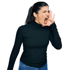 Young hispanic woman wearing casual clothes shouting and screaming loud to side with hand on mouth....