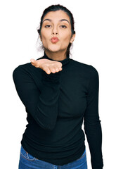 Young hispanic woman wearing casual clothes looking at the camera blowing a kiss with hand on air being lovely and sexy. love expression.