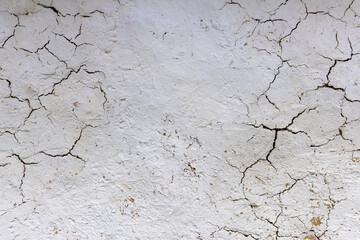 Close-up view of a cracked white painted straw wall texture