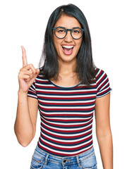 Beautiful asian young woman wearing casual clothes and glasses pointing finger up with successful...