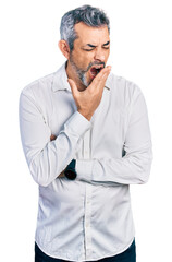 Middle age hispanic with grey hair wearing casual white shirt bored yawning tired covering mouth...