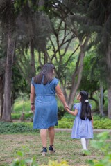 Fototapeta premium Family holding hands together and walking quietly on a park during a sunny day