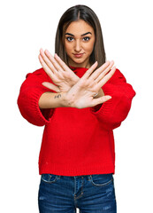 Beautiful brunette woman wearing casual winter sweater rejection expression crossing arms and palms...