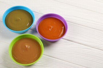 Baby food. Different purees in bowls on white wooden table. Space for text