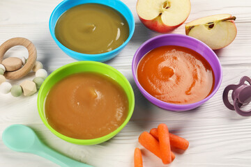 Baby food. Different purees in bowls, fresh ingredients, toy and soother on white wooden table