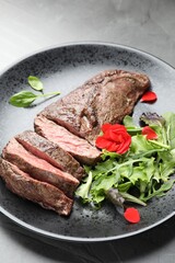 Pieces of delicious grilled beef meat and greens on table, closeup