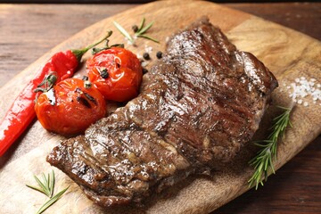 Delicious roasted beef meat, vegetables and spices on wooden table, closeup