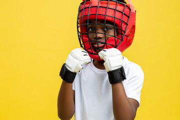 Dark-skinned little boy fighter in protective boxing helmet and gloves