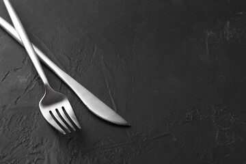 Beautiful cutlery set on black table. Space for text