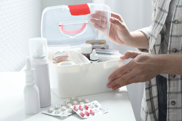 Woman opening first aid kit at white table indoors, closeup