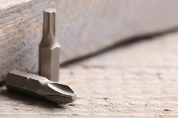 Different screwdriver bits on wooden table, closeup. Space for text - obrazy, fototapety, plakaty