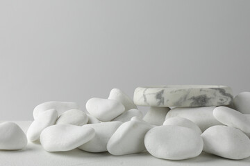 Presentation for product. Stone podium and white pebbles on table against light background. Space for text