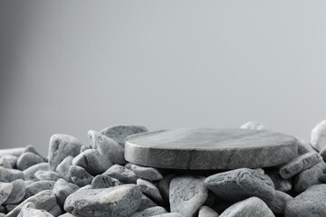 Presentation for product. Stone and pebbles on grey background. Space for text