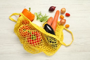 Foto op Canvas String bag with fresh vegetables on white wooden background, flat lay © New Africa
