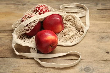 Fotobehang String bag with fresh apples on wooden background © New Africa