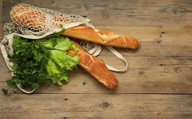 Foto op Plexiglas String bag with fresh baguettes, lettuce and herbs on wooden background, top view. Space for text © New Africa
