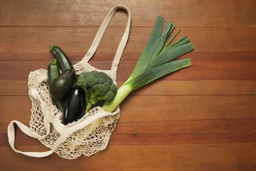Foto op Canvas String bag with fresh vegetables and avocado on wooden background, top view. Space for text © New Africa