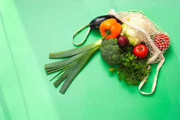 Foto op Plexiglas String bag with fresh vegetables and herbs on green background, top view © New Africa