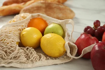 Fotobehang String bag with fresh fruits on light table, closeup © New Africa