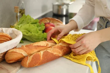 Fotobehang Woman taking baguettes out from string bag at countertop, closeup © New Africa