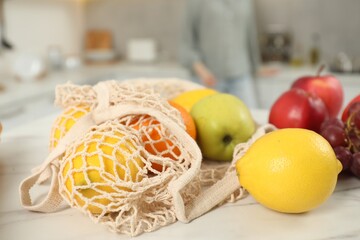 String bag of fresh fruits at light marble table, closeup