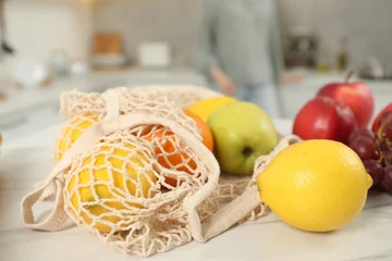 Fotobehang String bag of fresh fruits at light marble table, closeup © New Africa